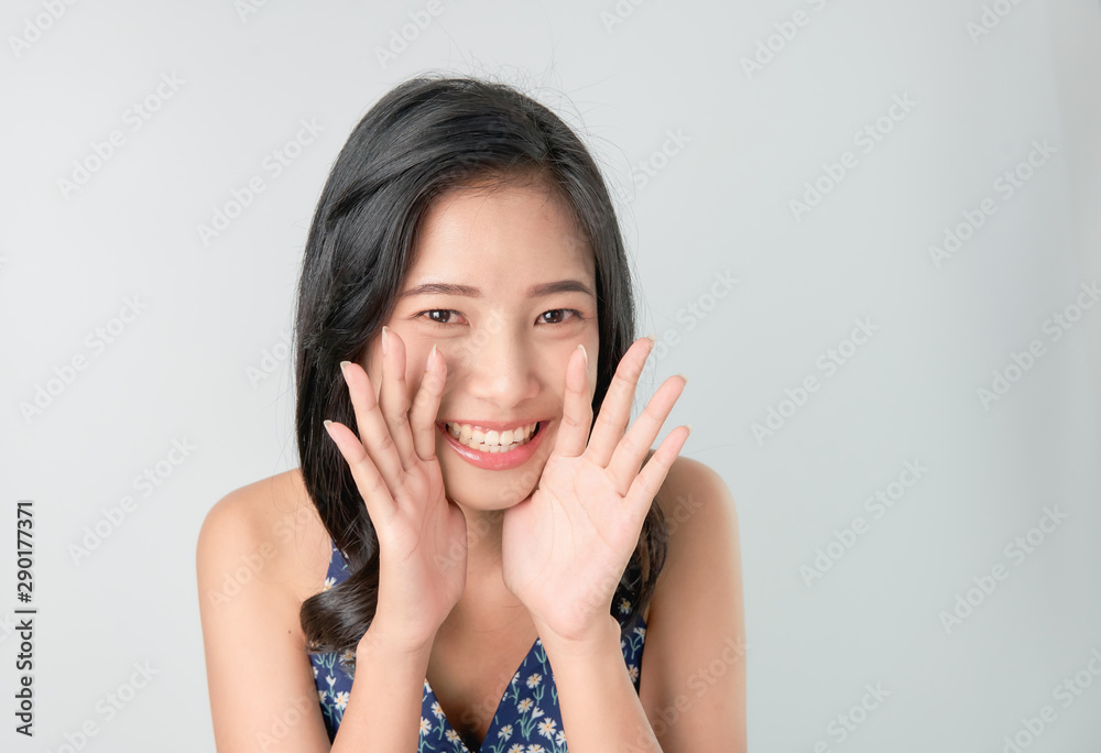 Attractive young asian woman announcing with hands to the mouth and telling a secret, isolated on light blue background Attractive young asian woman announcing with hands to the mouth and telling a secret, isolated on light blue background
