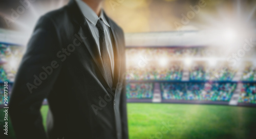 Manager leadership concept, businessman in black suit stand at soccer stadium in background. photo