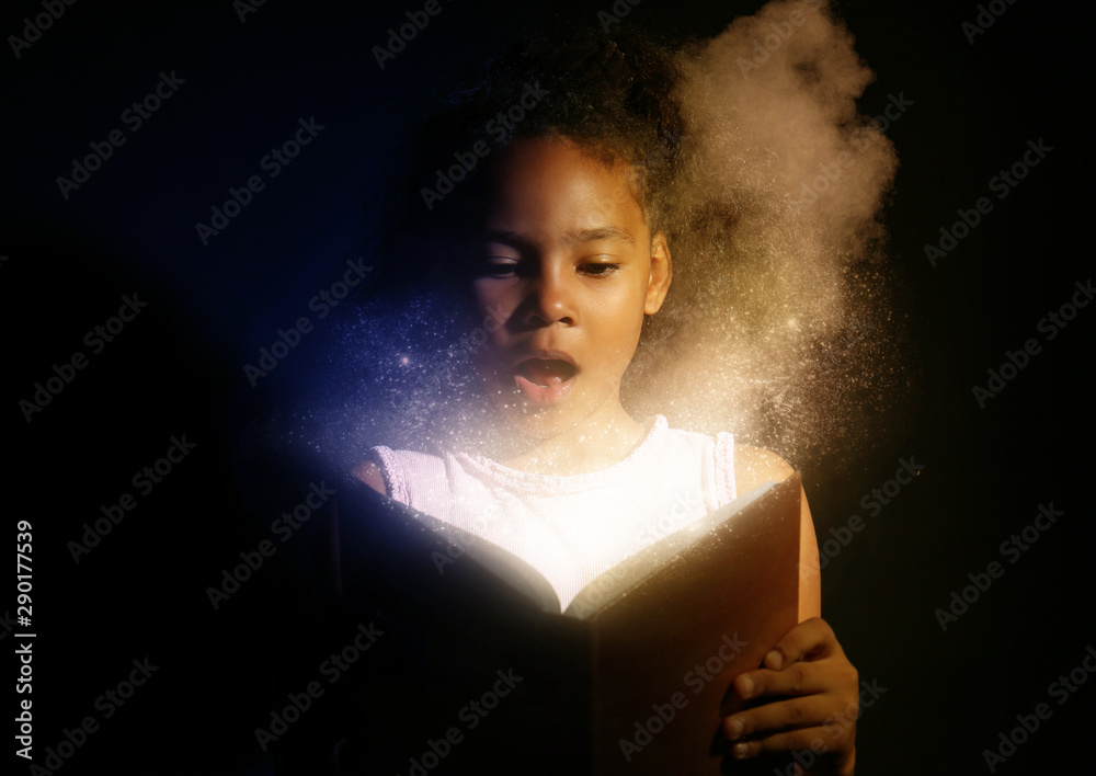 Surprised African-American girl reading magic book on dark background - obrazy, fototapety, plakaty 