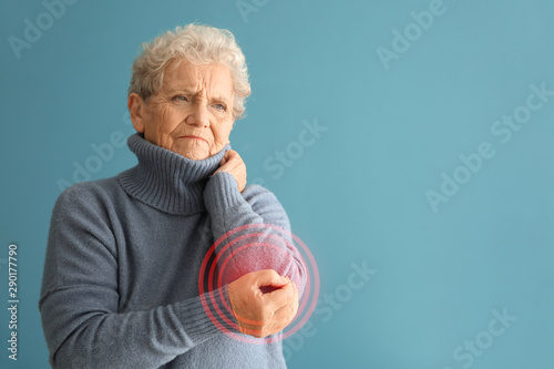 Senior woman suffering from pain in elbow on color background photo