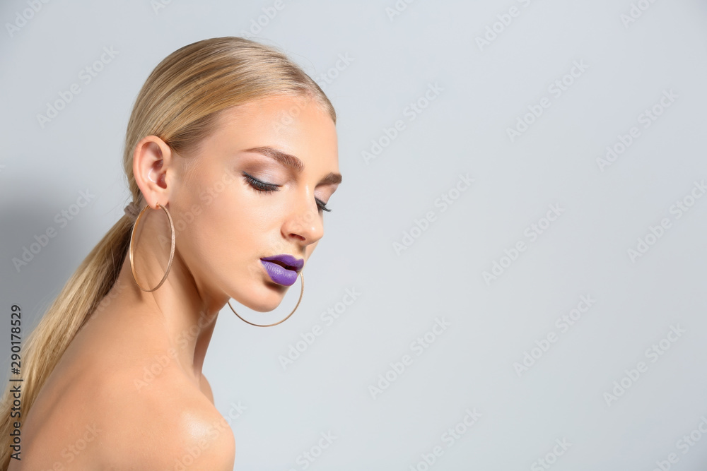 Obraz premium Beautiful young woman with bright purple lipstick on light background