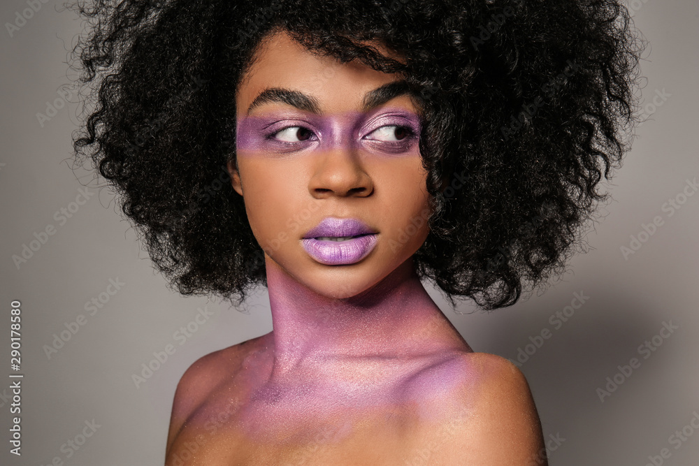 Fototapeta premium African-American woman with purple paint on her body against grey background