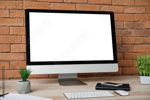 Stylish workplace with modern computer near brick wall