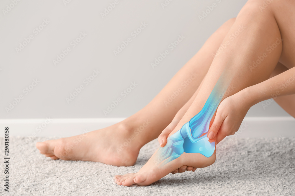 Woman suffering from pain in foot while sitting on carpet Woman suffering from pain in foot while sitting on carpet