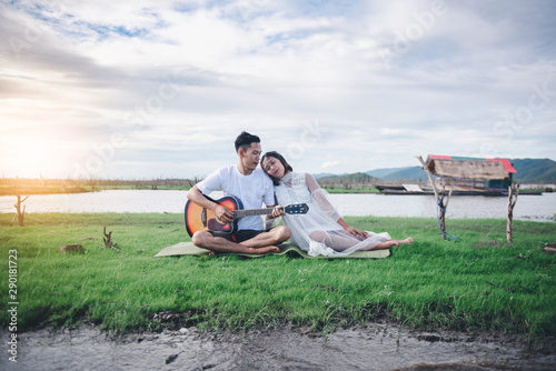 Asian husband playing guitar and enjoy with his pregnant wife outdoor Asian Married couple and family concept.