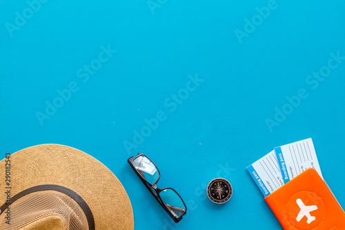 Tourist concept. Passport with airplane, tickets, hat, glasses on blue background top view copy space frame