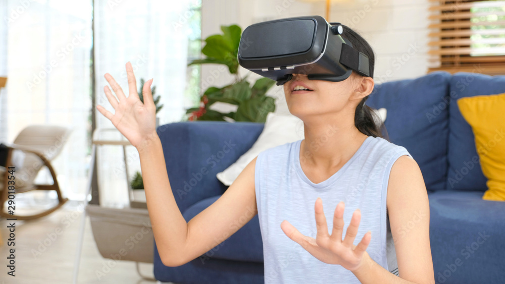 Young beautiful asian woman exciting in VR headset looking up and trying to touch objects in virtual reality at home living room, people leisure technology lifestyle Young beautiful asian woman exciting in VR headset looking up and trying to touch objects in virtual reality at home living room, people leisure technology lifestyle