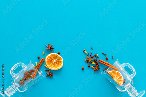 Mulled wine concept. Spices and dried orange in glasses on blue background top view space for text