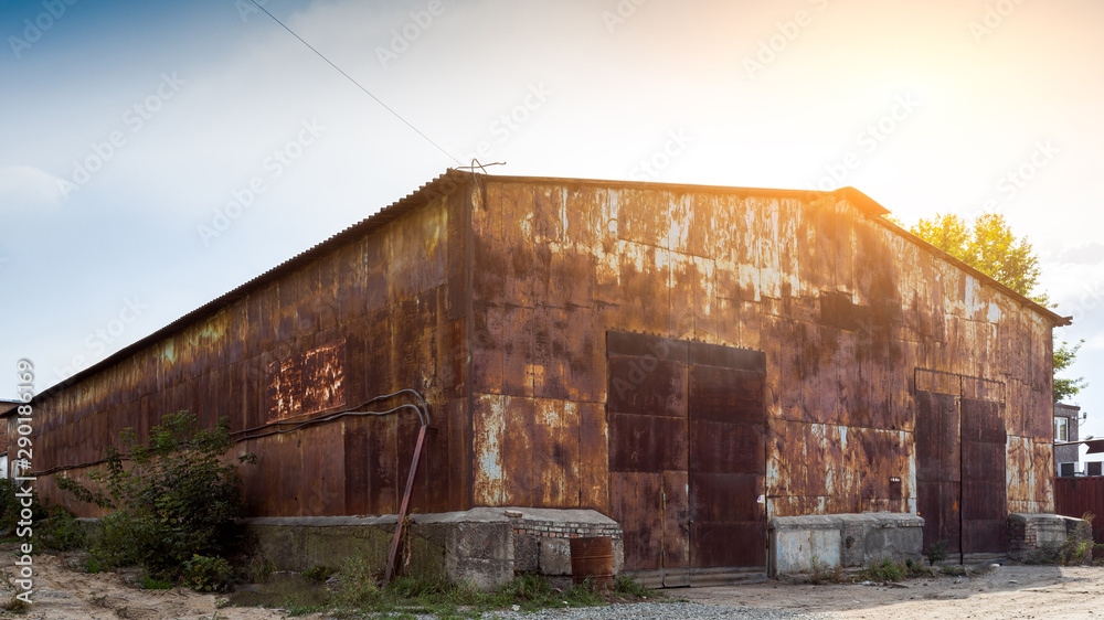 Old brown warehouse with sheet metal cladding with street lights. Industrial concept of transportation, loading and storage of goods