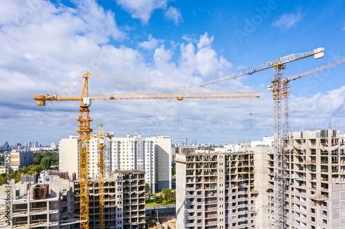 industrial tower cranes against blue sky background. panoramic view of city construction site. development of new residential area