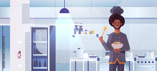 male professional chef cook holding plate with porridge and spoon african american man in uniform tasting dish cooking food concept modern restaurant kitchen interior flat portrait horizontal
