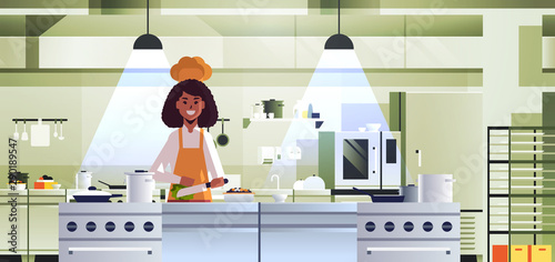 female professional chef cook chopping vegetables on carving board african american woman in uniform preparing salad cooking food concept modern restaurant kitchen interior portrait horizontal