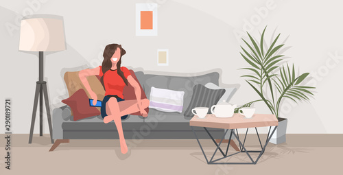 girl sitting on couch woman using smartphone communication concept modern living room interior flat full length horizontal