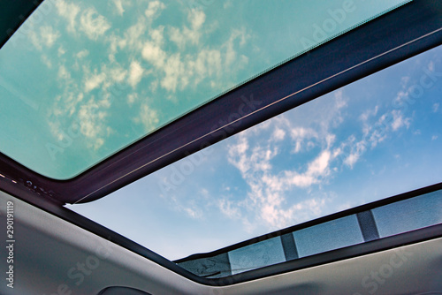 Blue sky through an open car sunroof , view from the passenger compartment,open sunroof look up to sky.. photo