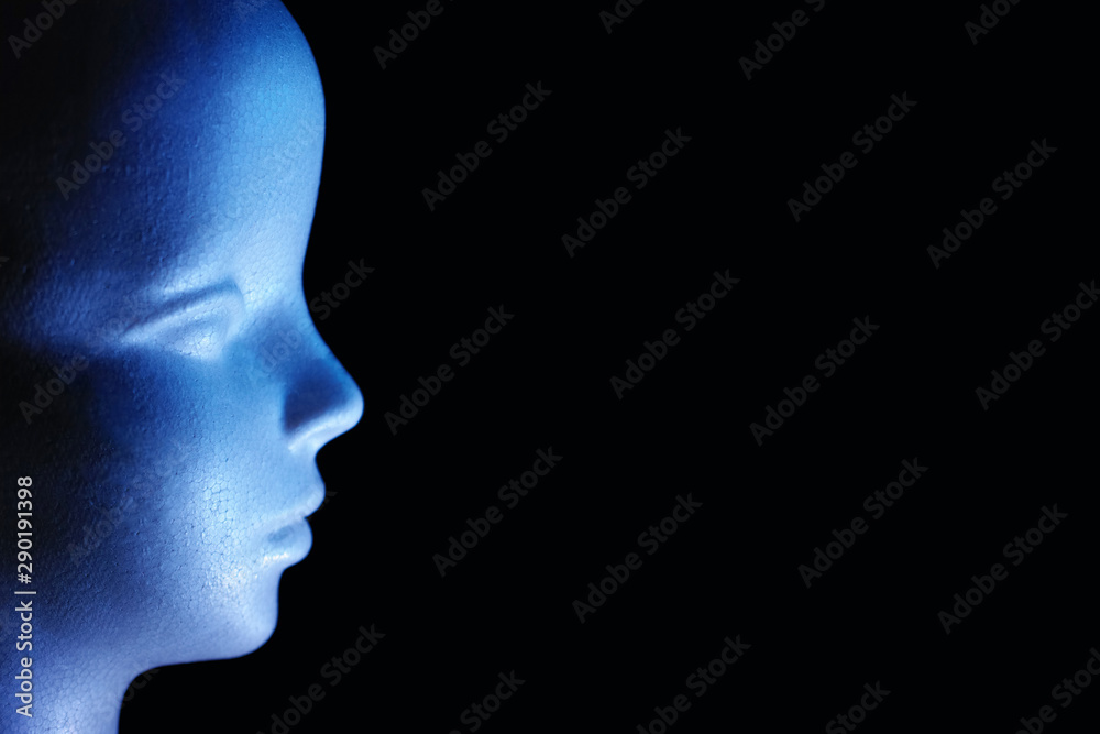 青色の光で照らした発泡スチロール製の人形の横顔と黒いコピースペース　