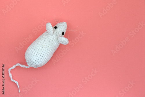 White crocheted rat on a pink background. Mouse symbol 2020 new year. Top view, copy space