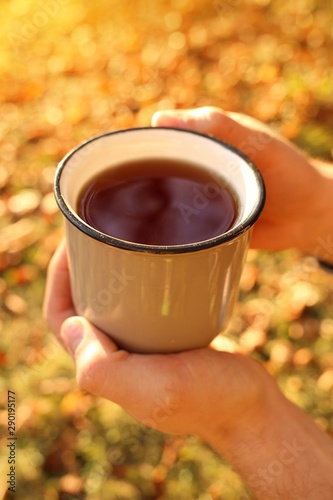 Autumn coffee. Autumn tea. mug of hot drink in male hands on a bright orange blurred vegetable background.Autumn cozy mood