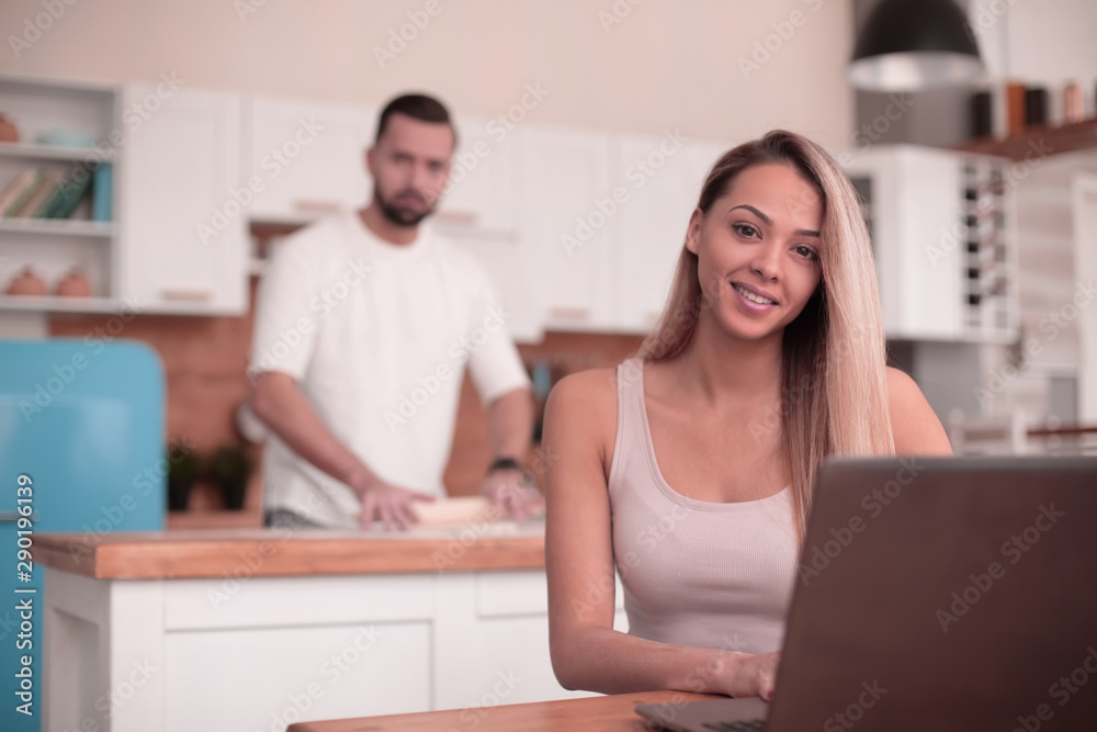 young woman sitting in front of open laptop in kitchen young woman sitting in front of open laptop in kitchen