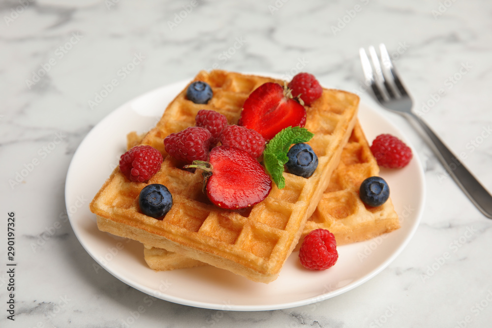Delicious waffles with fresh berries served on white marble table Delicious waffles with fresh berries served on white marble table