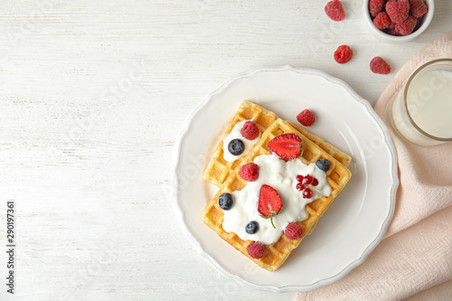 Flat lay composition with delicious waffles and fresh berries on white wooden table. Space for text