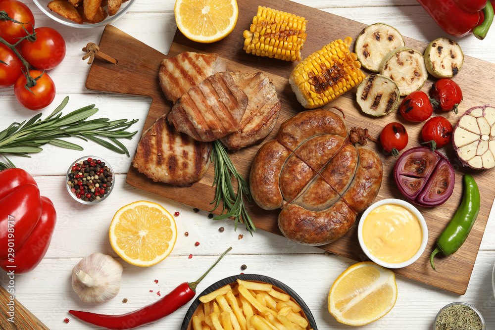 Barbecued meat and vegetables on white wooden table, flat lay Barbecued meat and vegetables on white wooden table, flat lay