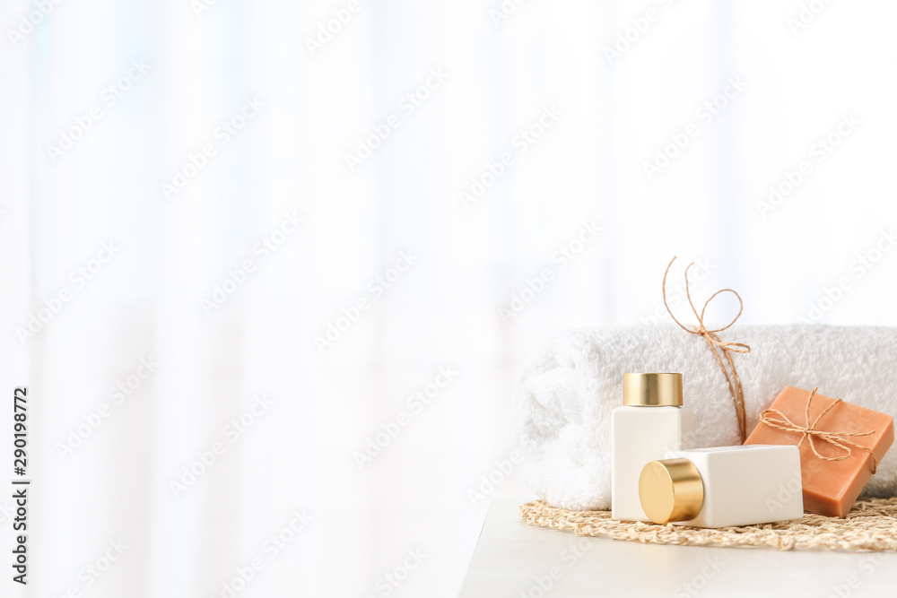 Cosmetic bottles, handmade soap and towel on light grey table indoors, space for text. Spa treatment