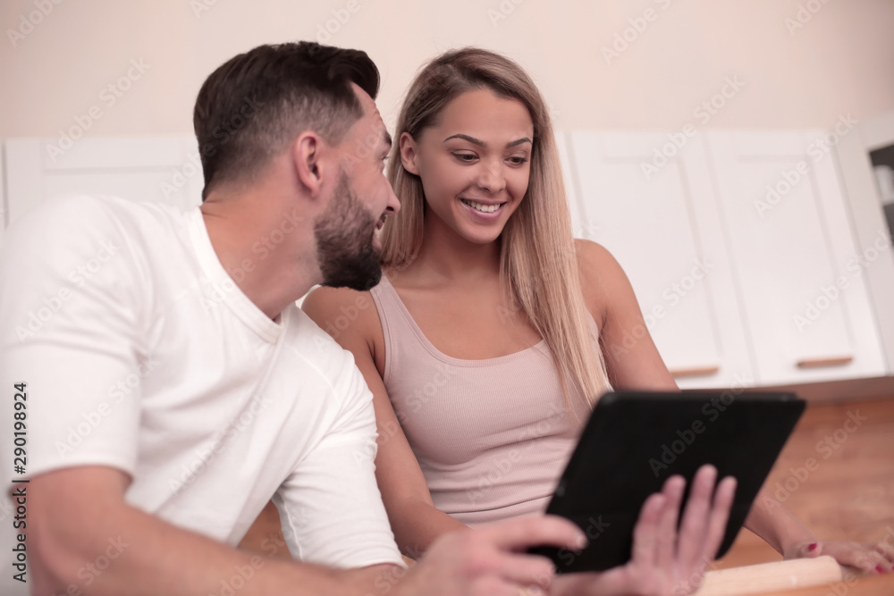 Young couple surfing the web with tablet at home kitchen Young couple surfing the web with tablet at home kitchen