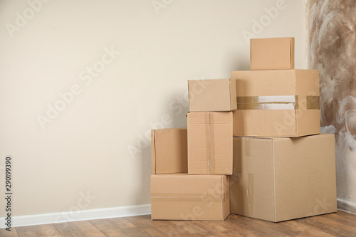 Pile of cardboard boxes near light wall indoors. Space for text