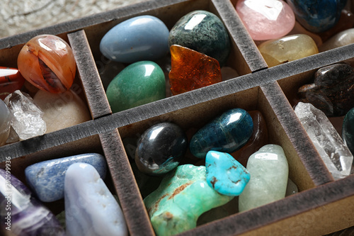 Box with different beautiful gemstones on table, closeup photo