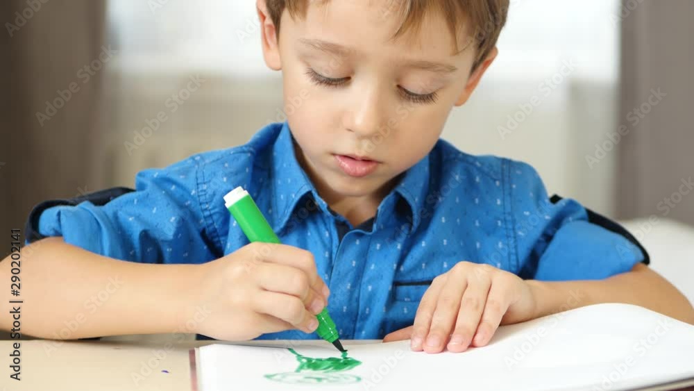 A little boy imagines, draws sitting at the table. The child draws bright felt pen. A little boy imagines, draws sitting at the table. The child draws bright felt pen.