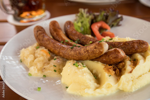 Bayrische Bayreuther Bratwürste mit Sauerkraut und Kartoffelpüree auf Holz Tisch Hintergrund in Biergarten