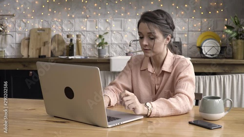 Adult dark haired woman working on laptop in the kitchen at home, time lapse effect. Stock footage. Modern technologies and interior concept, female typing a message. photo