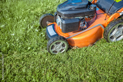 Gasoline lawn mower cutting grass, close-up. Backyard care concept