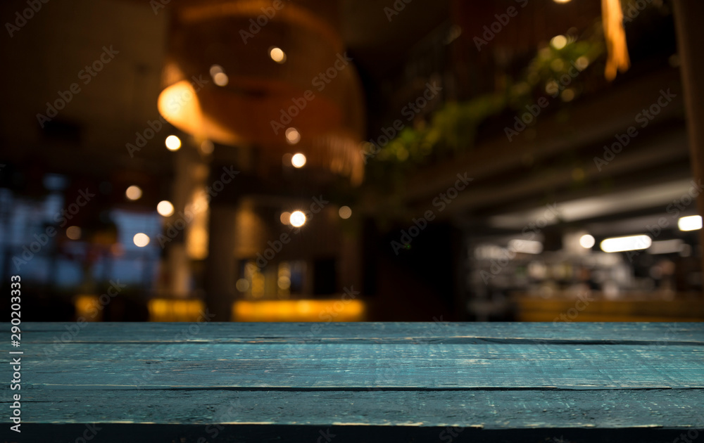 Empty wood table top on blur light gold bokeh of cafe restaurant in dark background