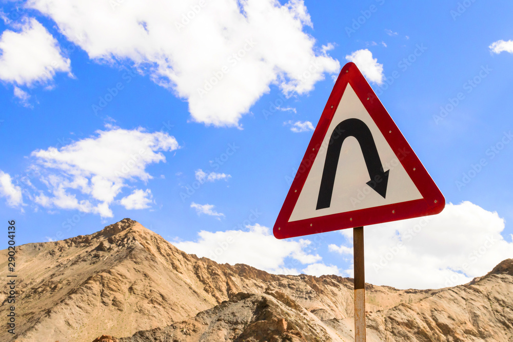 Curves ahead highway sign in Leh Ladakh, Jammu and Kashmir, India. Traffic sign with mountain and blue sky background.