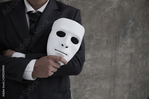Businessman holding white mask in his hand dishonest cheating agreement.Faking and betray business partnership concept photo