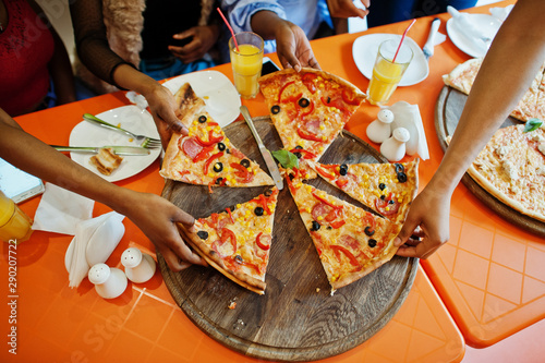 Hands of african gilrls taking pizza slices on restaurant.