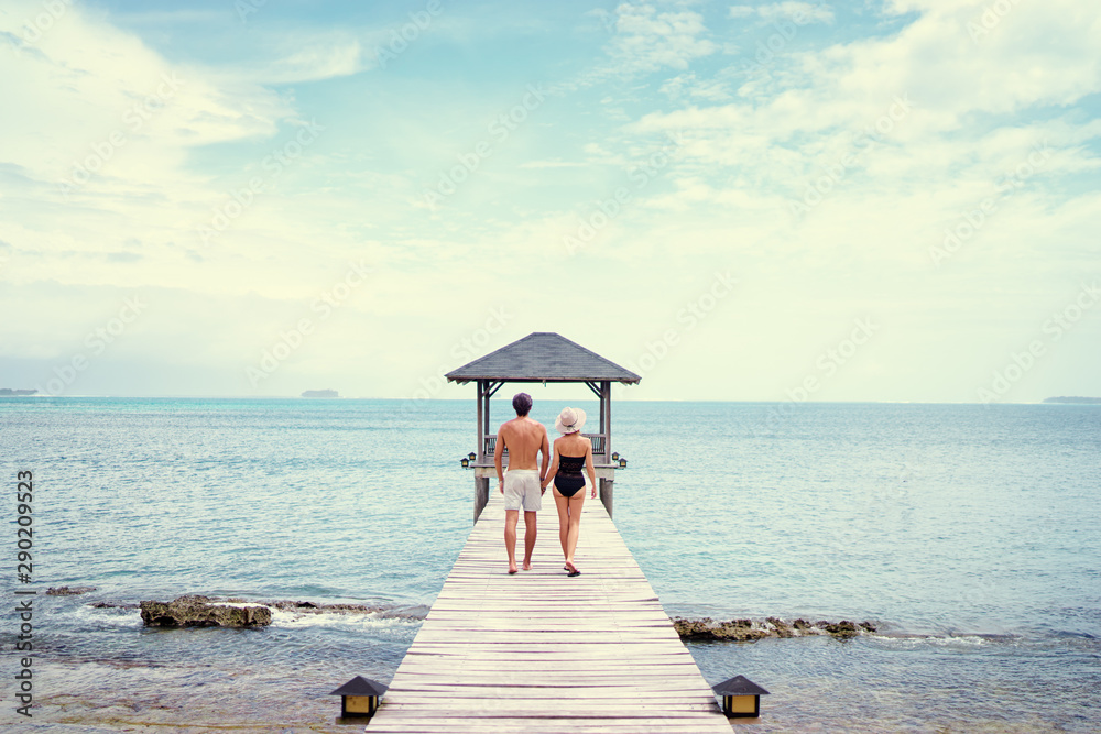 Honey moon on the sea shore. Back view of loving couple walking together on wooden pier.