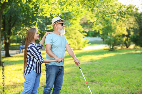 Blind mature man with daughter walking in park