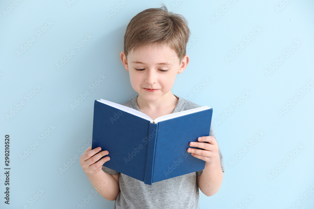 Little boy reading book on color background - obrazy, fototapety, plakaty 
