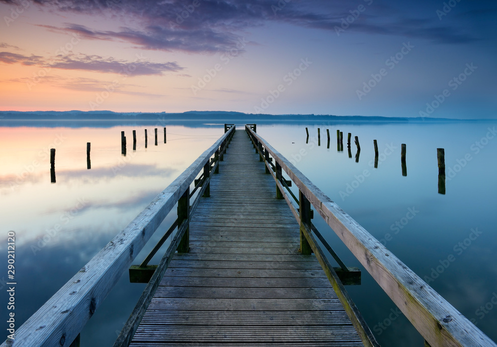 Long Wooden Pier into Calm Lake at Sunrise	