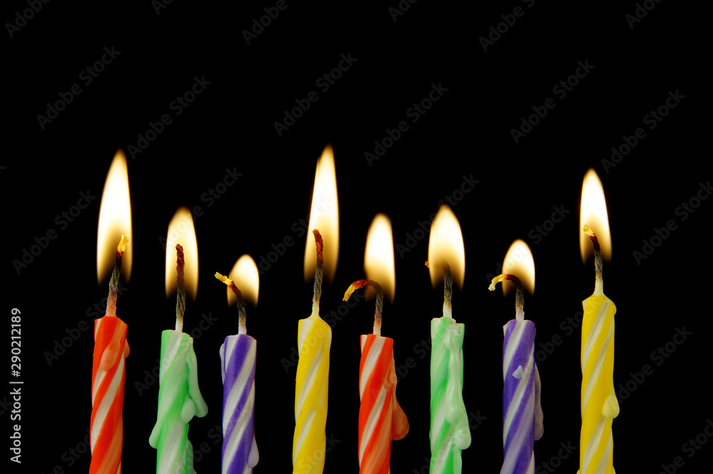 Colorful burning birthday candles on black Colorful burning birthday candles on black