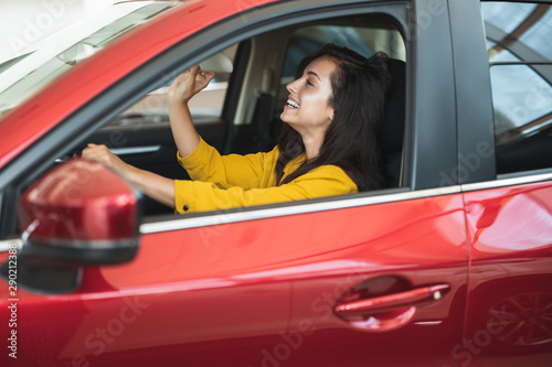 beautiful brunette woman looking for new car in dealership center checking the interior