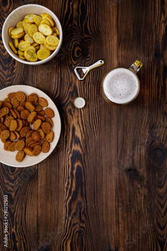 Beer glass with bottle cap and snack on wood background. top view. copy space