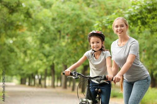 Mother teaching her daughter to ride bicycle outdoors © Pixel-Shot