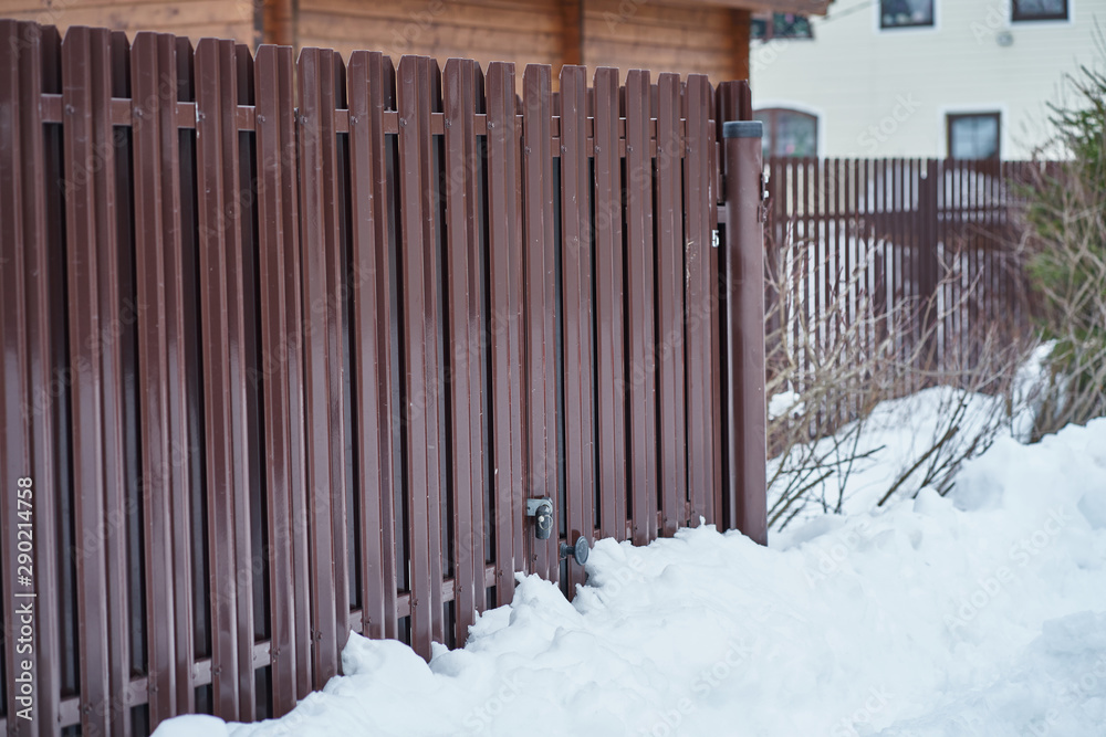 Fototapeta premium Metal Fence and snow in countryside, gate with padlock, side view