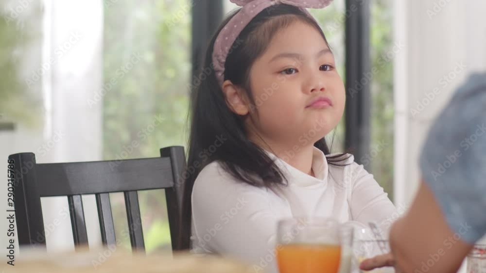 Asian Japanese daughter bored with food. Lifestyle kids sad dislike food upset breakfast meal in the kitchen at home in the morning. Slow motion shot. Asian Japanese daughter bored with food. Lifestyle kids sad dislike food upset breakfast meal in the kitchen at home in the morning. Slow motion shot.