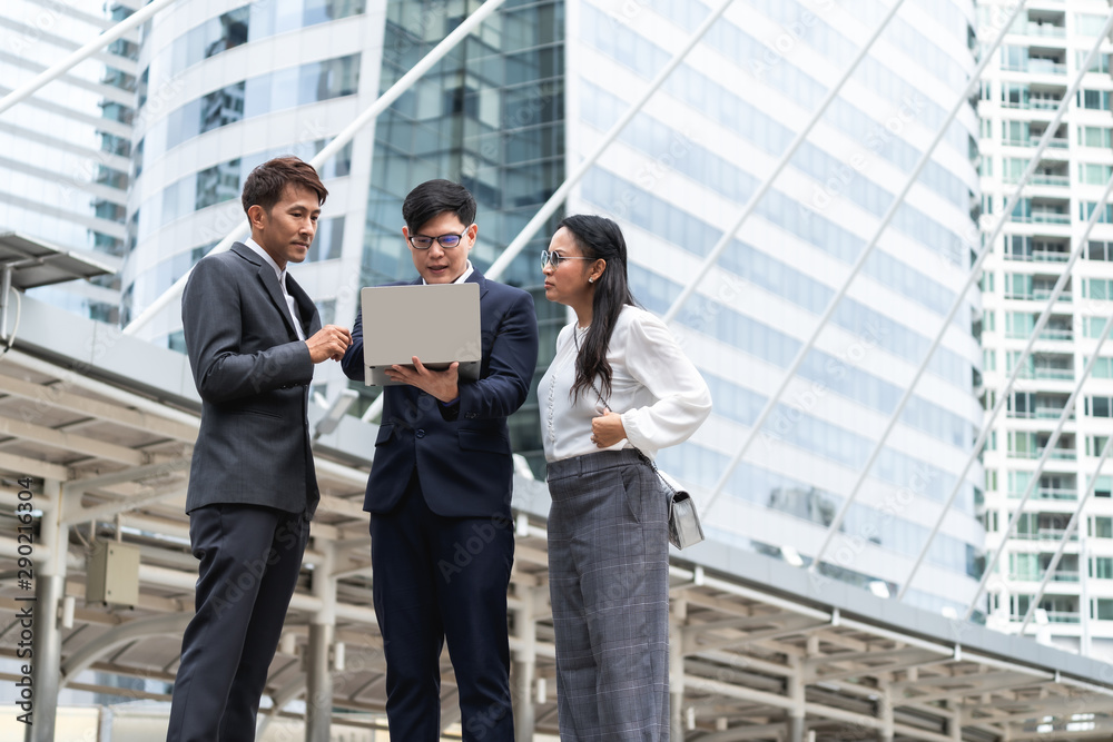 group of asian business people working and discussing something positive with his mature colleague and using a laptop at outdoor in the capital group of asian business people working and discussing something positive with his mature colleague and using a laptop at outdoor in the capital