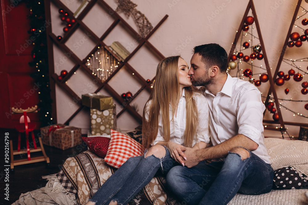 Happy cheerful family couple hugging each other and smiling together in cozy new year decorated home with christmas eve and lights. Family, christmas holidays concept