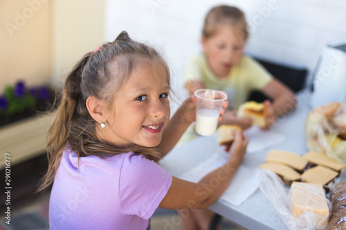 Little girl at the table eats a pie with milk